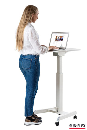 kvinna som står framför ett litet höj och sänkbart skrivbord.