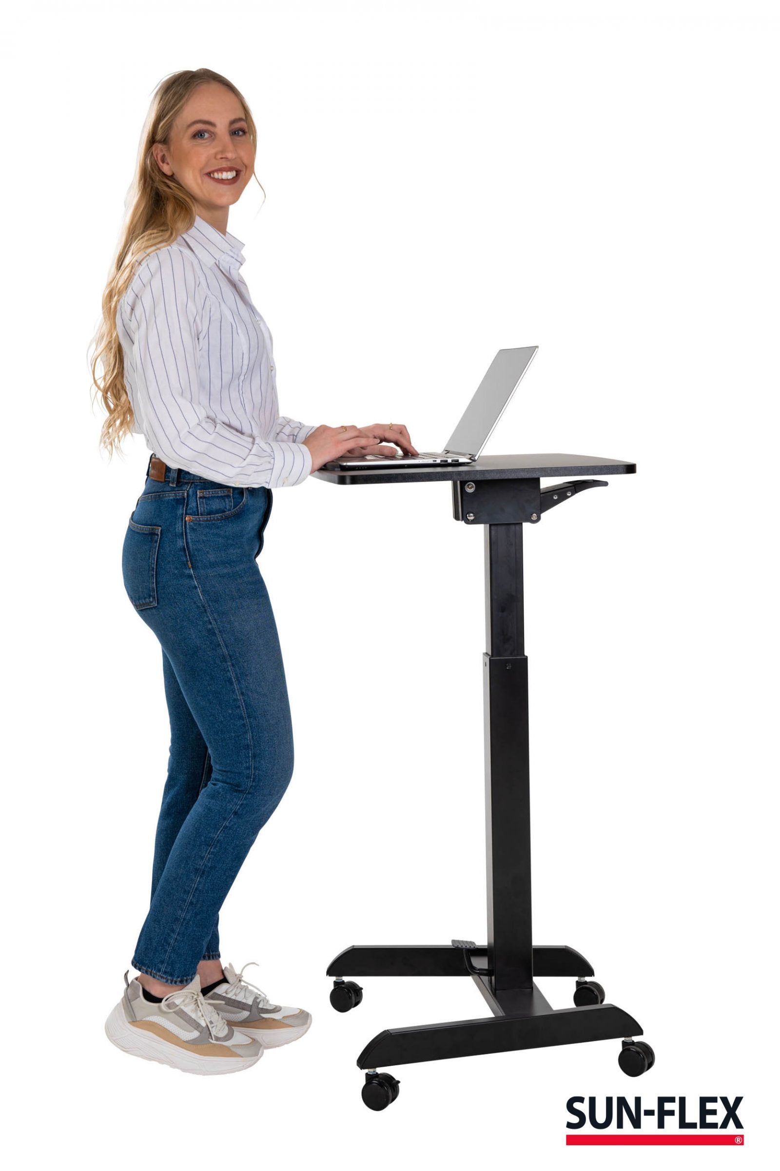Kvinna står och ler mot kamera framför sitt kompakta svarta lilla höj och sänkbara skrivbord.