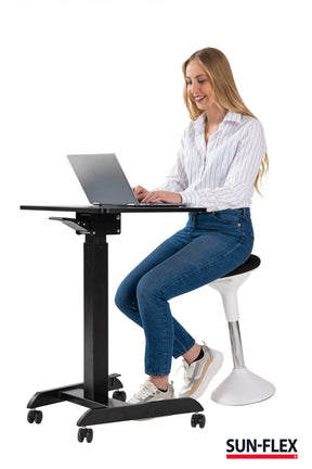 kvinna sitter framför sitt easy desk pro skrivbord och har suttit på balanspallen.
