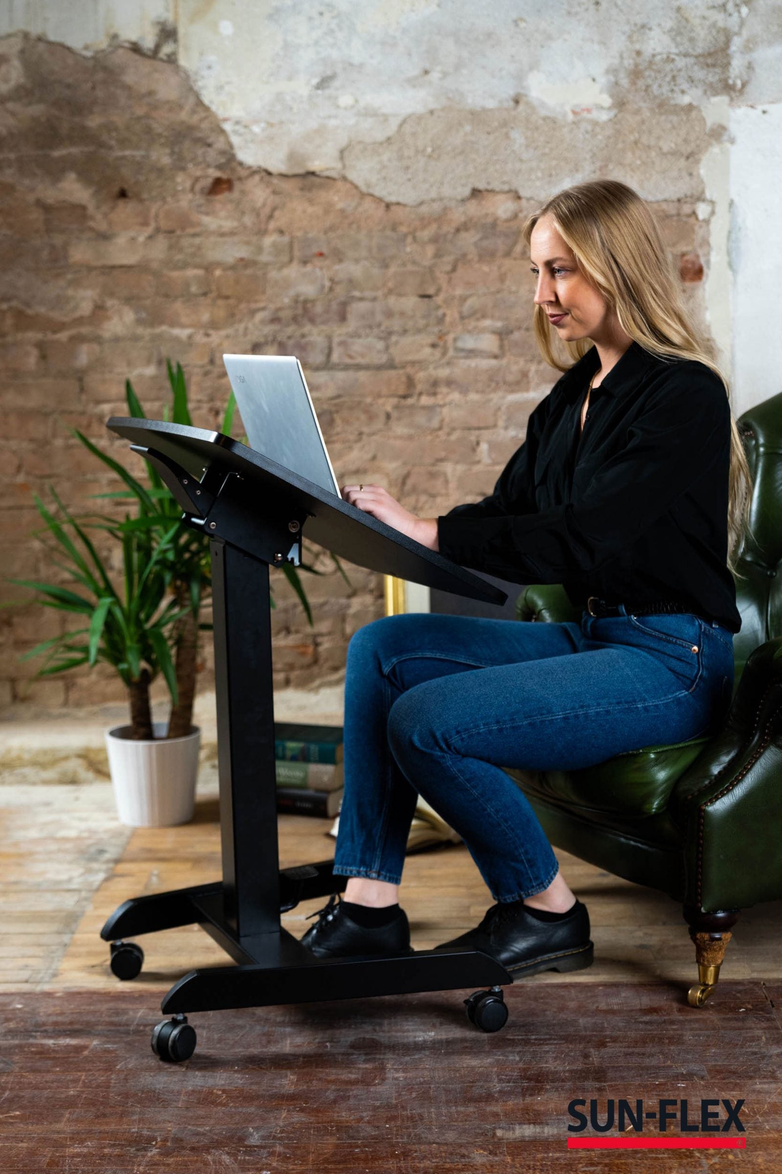 kvinna framför ett praktiskt kompakt skrivbord med portabilitet och höj- och sänkbar funktionalitet för hemmakontoret.