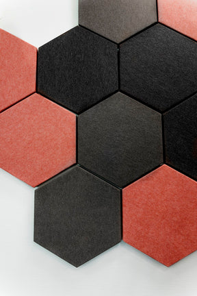 flera hexagonformade väggabsorbenter på vit vägg i färgerna, svart, mörkgrå och rost